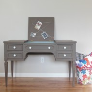 A taupe writing desk with milk glass knobs