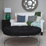 A Round, Black Tufted Ottoman with a Chrome Base