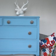 A sky blue dresser with some oversized knobs