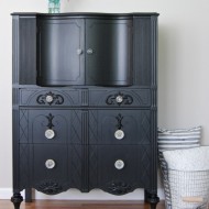 A tall black dresser with glass knobs