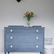 A grey-blue-purple dresser with soft blue knobs